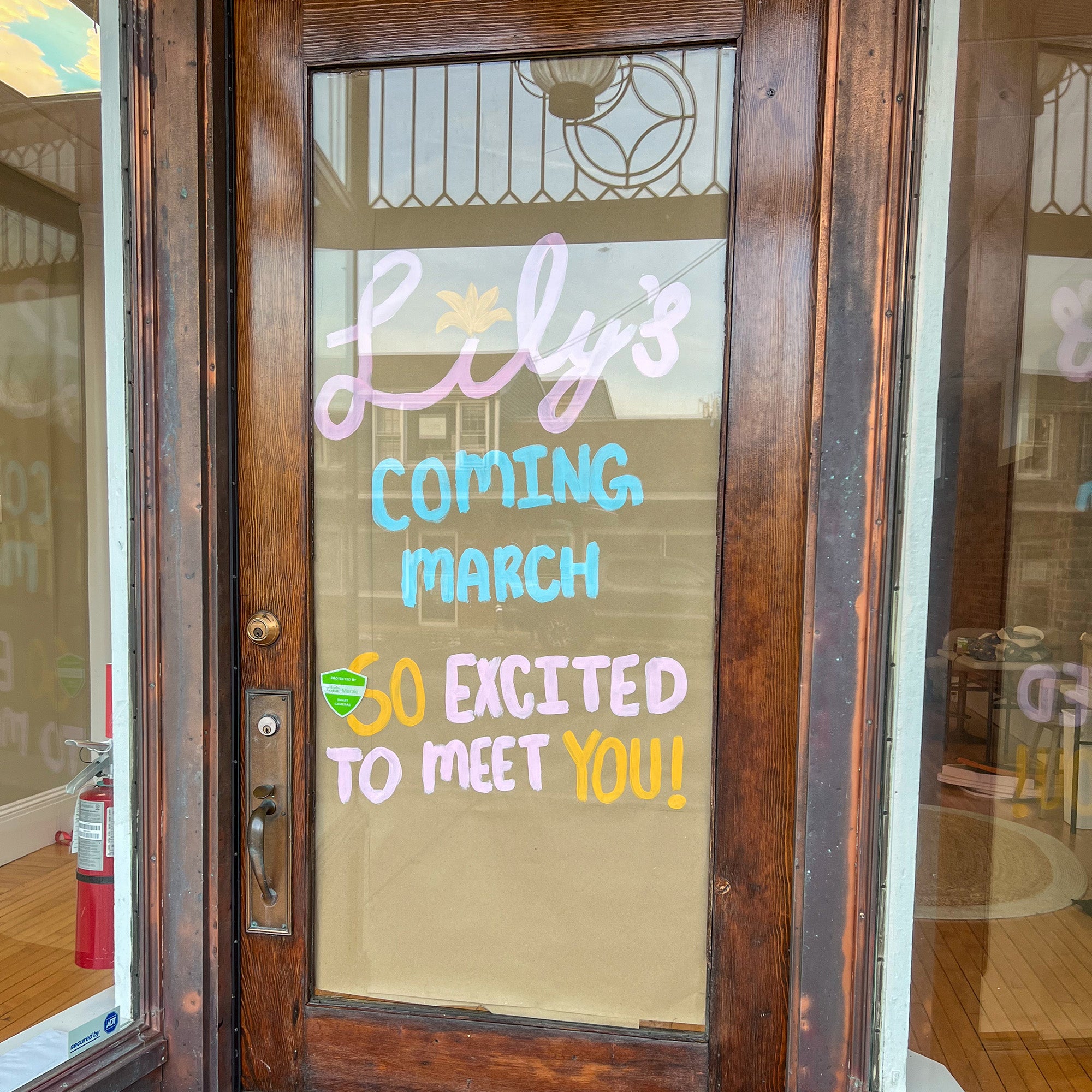 Decorative glass door with colorful text 'Lily's Coming March 5th Excited to Meet You!'